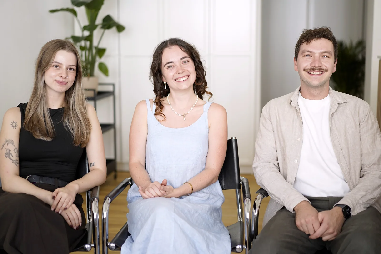 Drei Mitglieder des Loquio Teams sitzen lächelnd nebeneinander in der Praxis