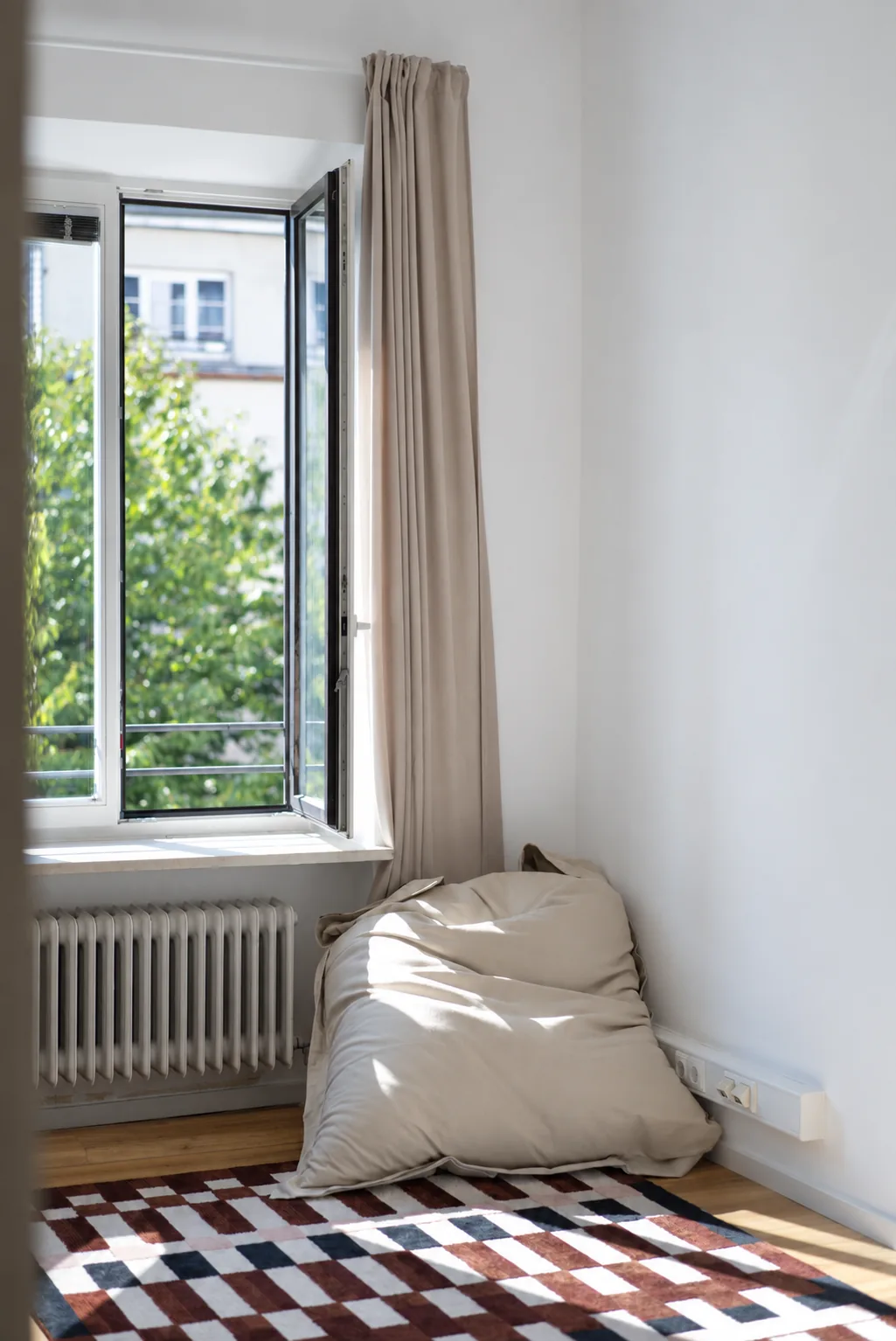 Sonniges Behandlungszimmer mit geöffnetem Fenster, Sitzsack und gemustertem Teppich